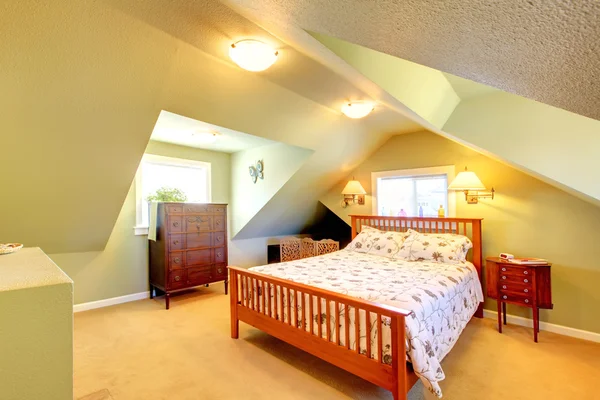 Attic bedroom with green walls and large bed.