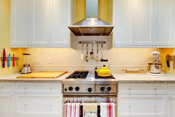 WHite kitchen cabinets with stove and hood.