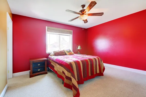 Red bedroom with bed and nighstand.