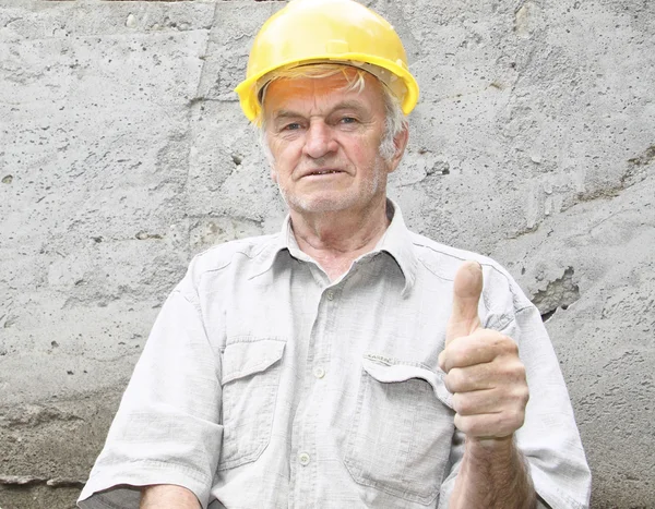 The man in a yellow helmet against a concrete wall shows an island to