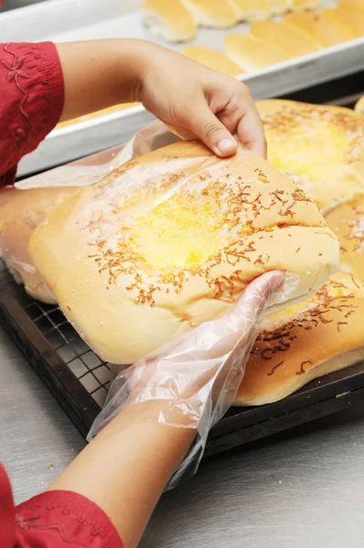 Bread packaging in plastic wearing plastic glove