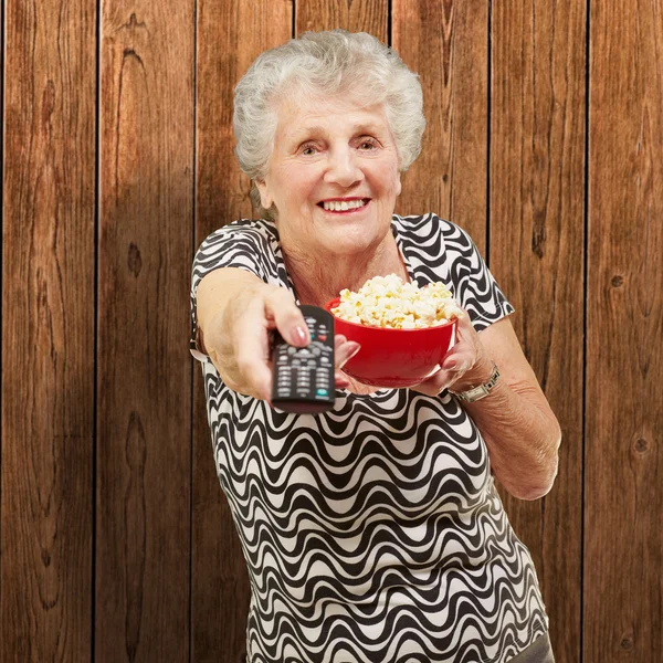 Portrait of senior woman holding pop corn bowl and changing chan
