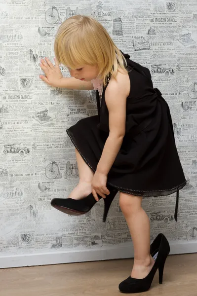 The little girl measures the mother\'s shoes with heels