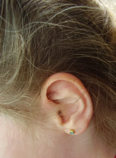 Ear of the child with an ear ring in ears