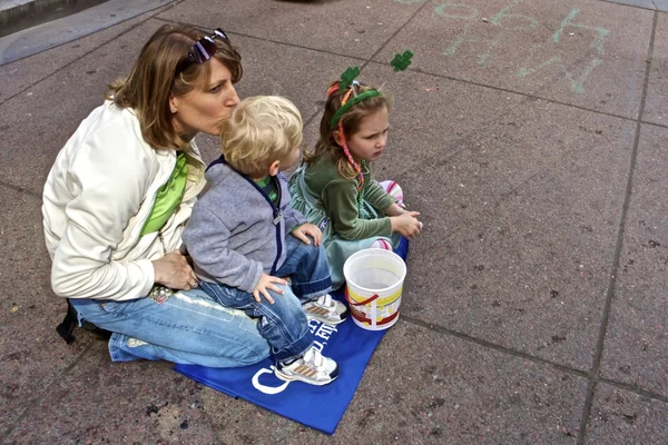 Young mom with two children watching Saint Patrick\'s Day Parade