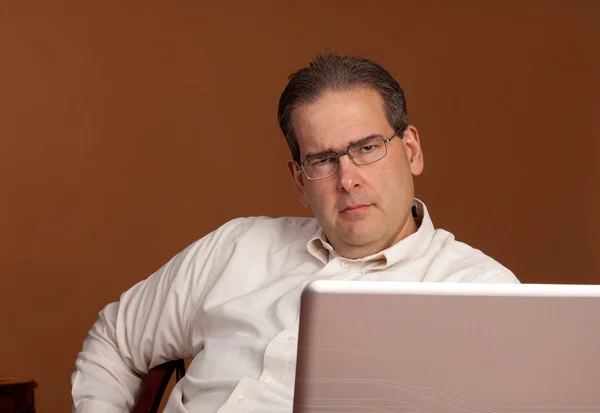 Scowling Middle Age man at Computer