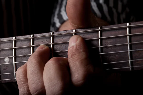 Close up shot of a mans left hand playing guitar