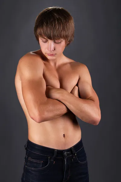 Tanned muscular young man. Isolated on dark background.