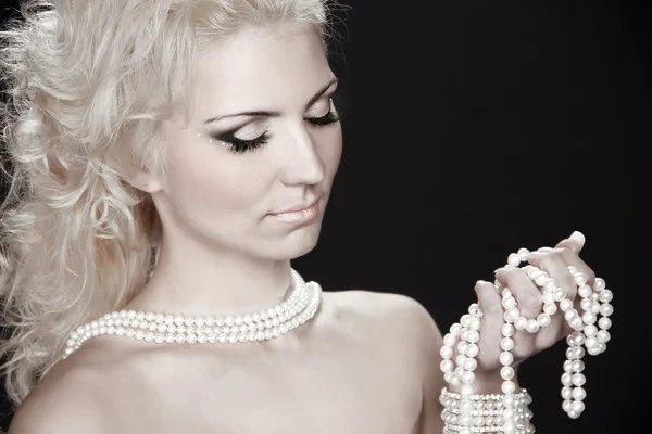 Beautiful fashion blonde woman with pearls, studio salon