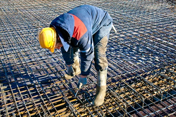 Industrial worker in hardhat and uniform installing binding wires