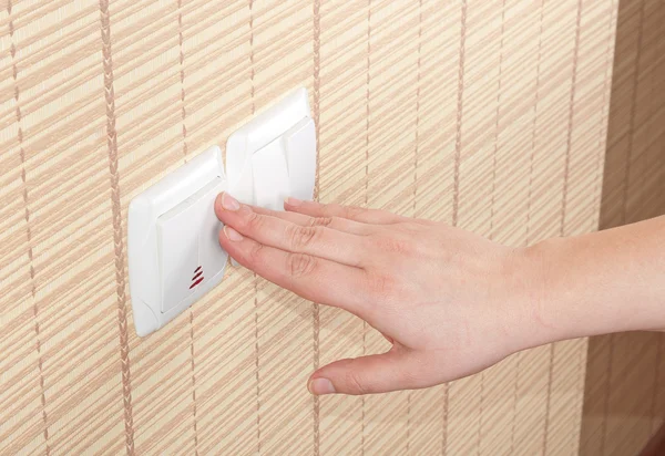 Hand pressed to switch on the wall