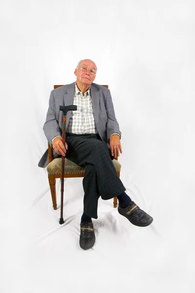 Old friendly man sitting in his armchair with walking stick