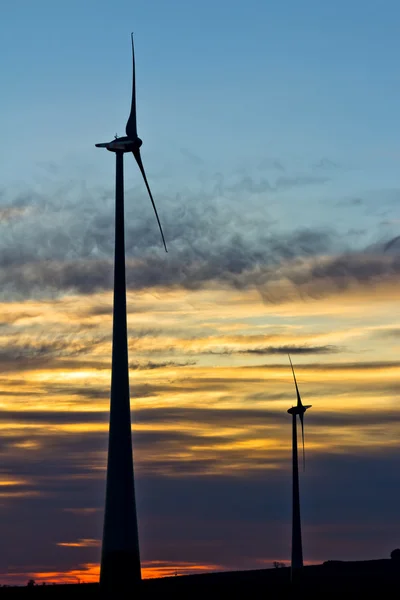Two wind turbines of the wind farm at sunset