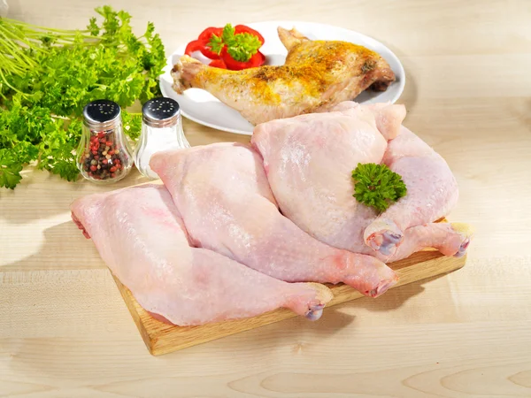 Fresh raw and roasted chicken legs arrangement on kitchen cuttin