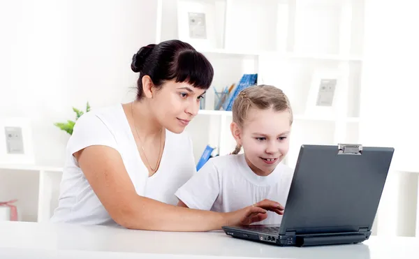 Mom and daughter are working together for a laptop