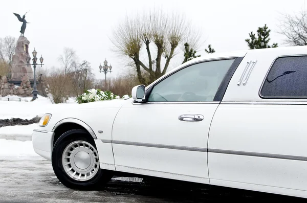 Part of white limousine, wedding car with flowers.