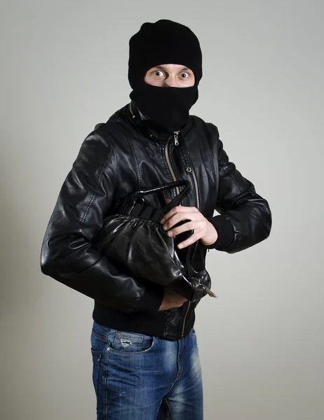 Portrait of scared male burglar with a handbag.