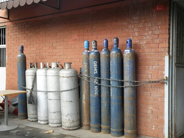Smaller and Bigger Gas Bottles in front of a Wall