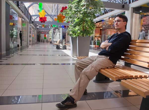 Portrait of young man on bench in mall