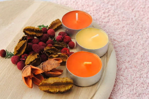Three candles with dried flowers in wooden dish