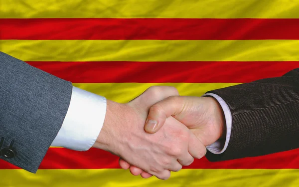 In front of flag of catalonia two businessmen handshake after g