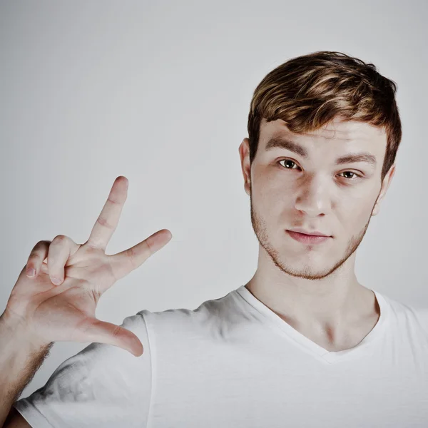 Young man holding up three fingers