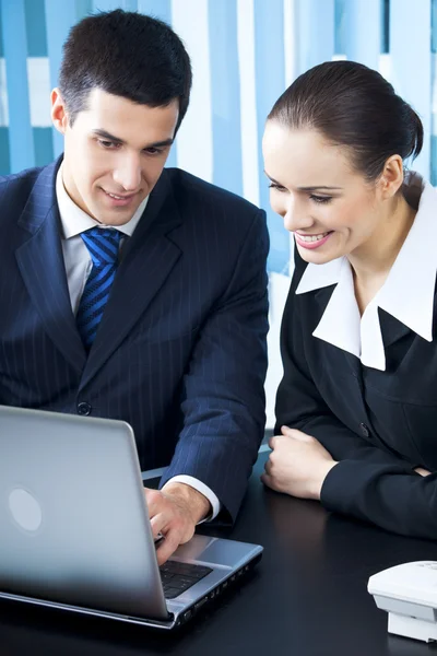 Two businesspeople working with laptop at office