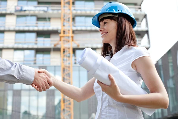 Young female construction engineer shaking hands at construction