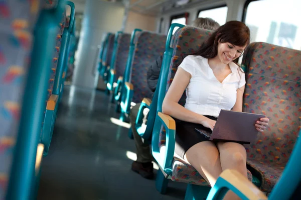 Happy young woman using a netbook on the train / bus