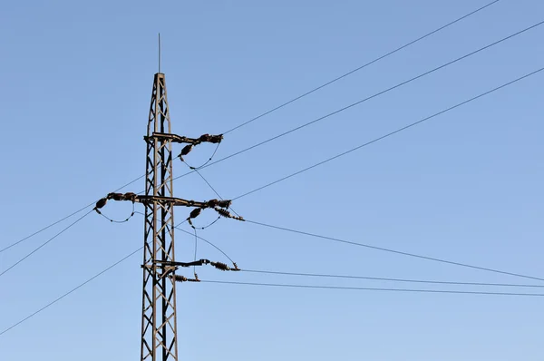 Electrical tower in field under blue sky