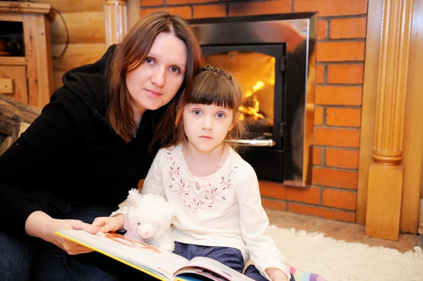 Mother and daughter sitting in front of fireplace