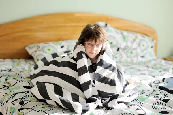 Sad child girl wrapped in blanket
