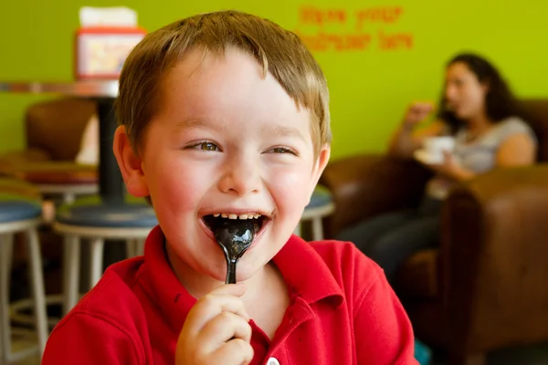 Young boy eating chocolate frozen yogurt at frozen yogurt or ice cream shop