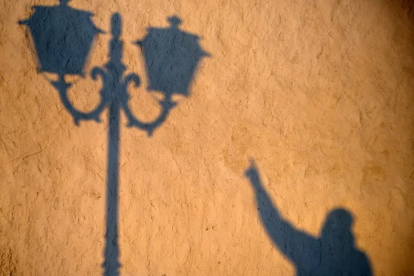 The lantern shadow on the yellow wall.
