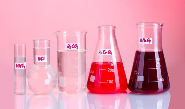 Test-tubes with various acids on pink background