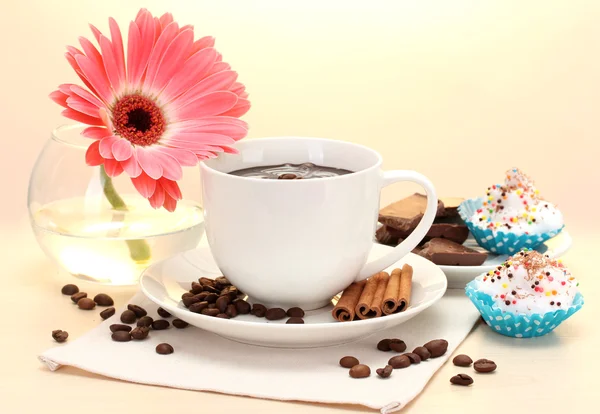 Cup of coffee and gerbera, beans, cinnamon sticks on wooden table