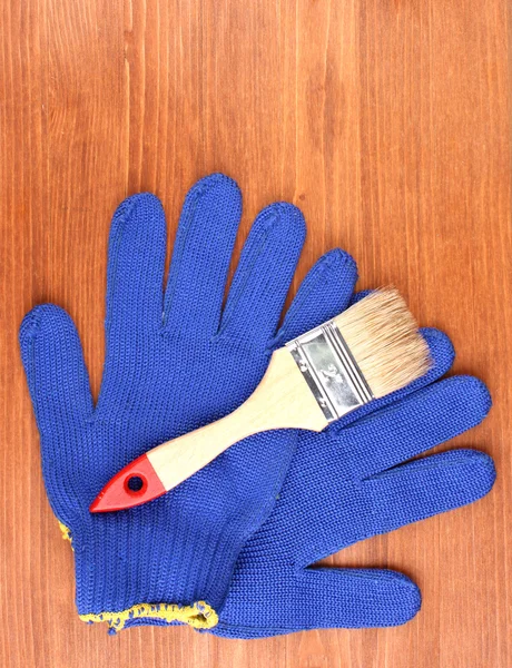Brush and gloves on wooden background