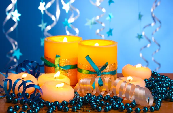 Beautiful candles, gifts and decor on wooden table on blue background