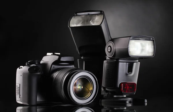 Black photocamera with flash on black background
