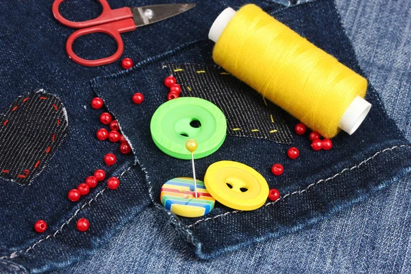 Rhomb-shaped patch on jeans with threads and buttons closeup