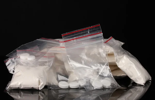 Cocaine and drugs in packages on black background