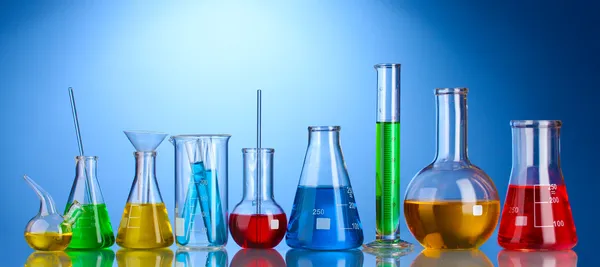 Different laboratory glassware with color liquid and with reflection on blu