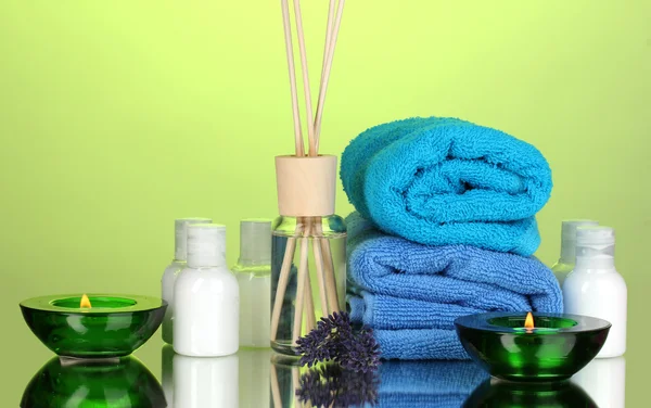 Bottle of air freshener, lavander and towels on green background
