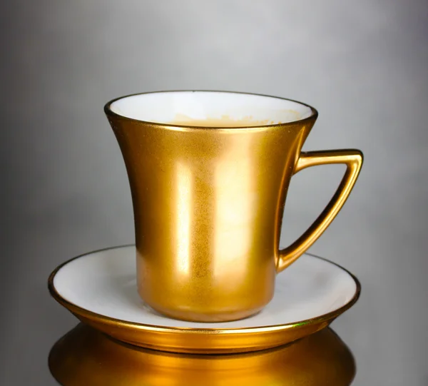 Golden cup of coffee on gray background