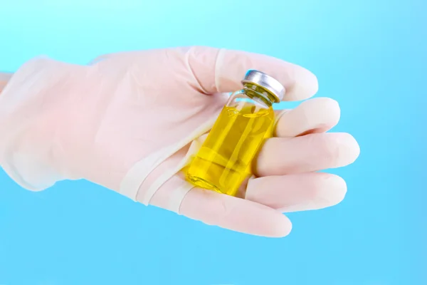 Medical ampoule in hand on blue background