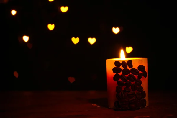Beautiful candle with coffee beans on wooden table on bright background