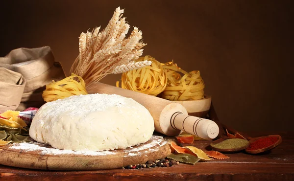 Ingredients for homemade pasta on wooden table on brown background