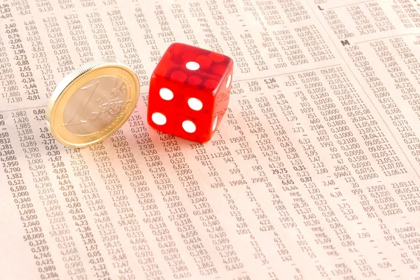 Euro coins and a red dice on the financial newspaper