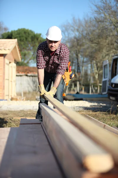 Carpenter arranging wooden beans on work-site