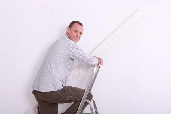 Man with step-ladder holding roll of wallpaper